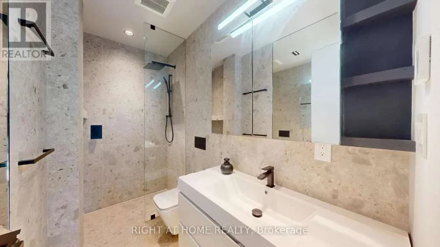 Bathroom with stone-look tile, a long vanity and a glass shower