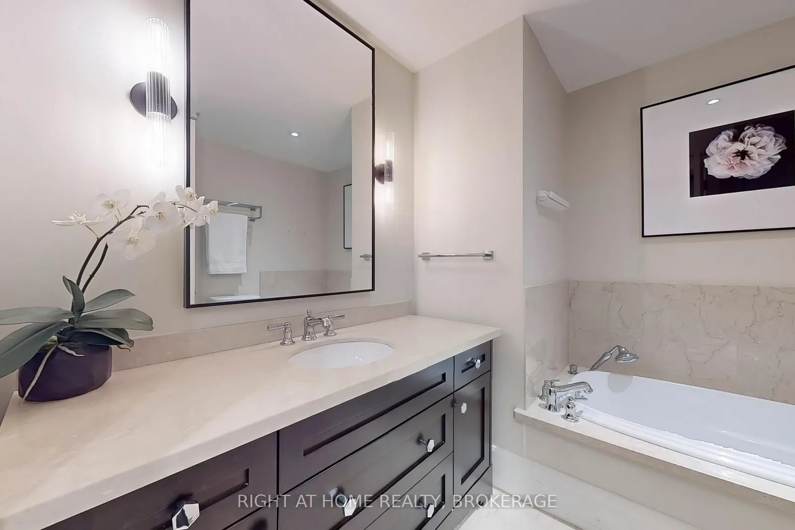 Bathroom with a soaker tub, stone counter and dark vanity