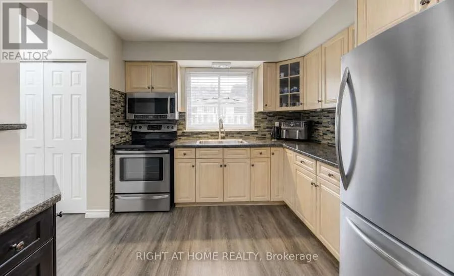 Kitchen with stainless steel appliances, light cabinets and a tiled backsplash