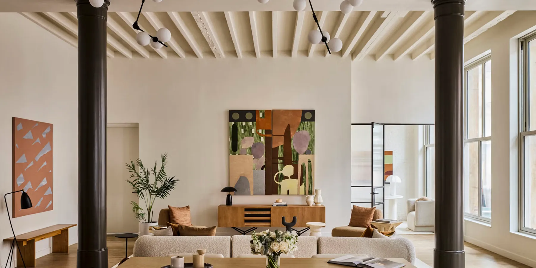 Sunlit loft living room with beamed ceilings and modern art